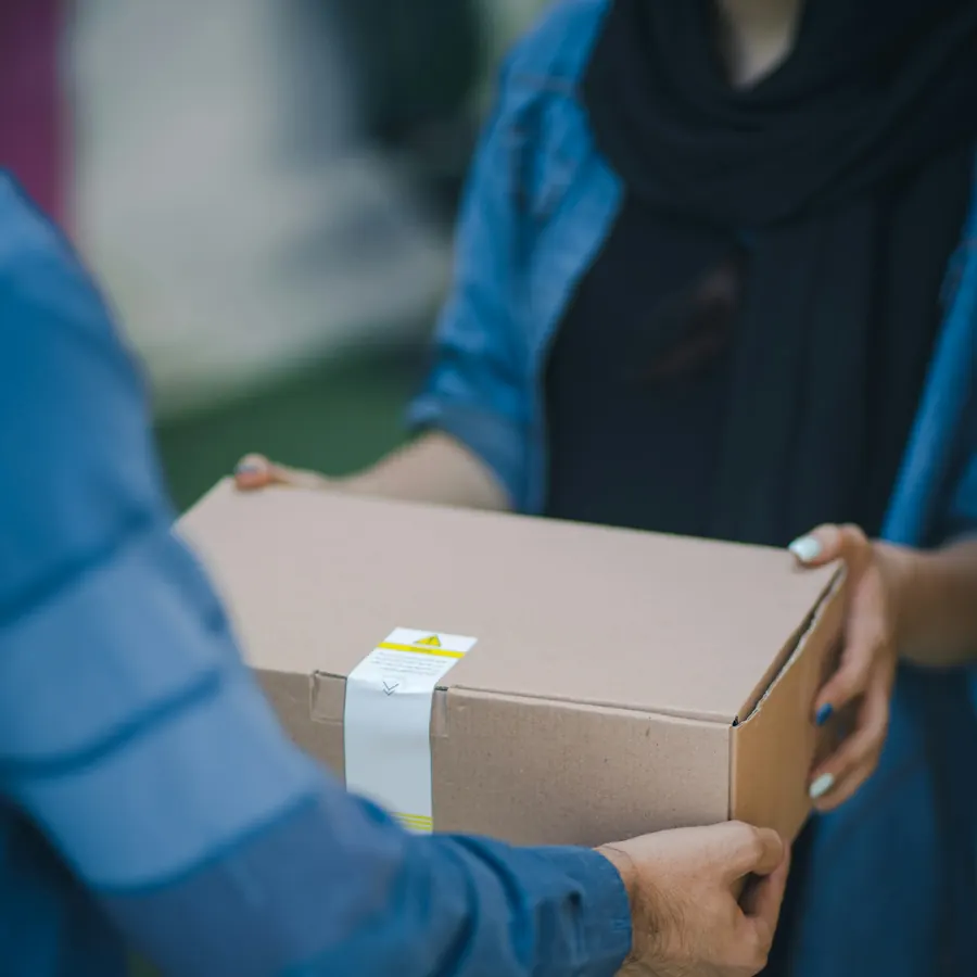 Warehouse worker handing over a labelled cardboard carton